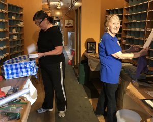 Carol and a Betty replace mail in display cases after thorough cleaning
